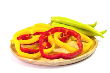 Fresh yellow and red pepper slices with green pepper in wooden plate on white background