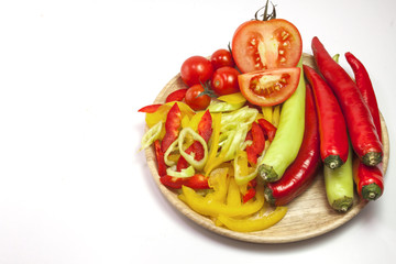 Fresh yellow and red pepper slices in wooden plate on white background