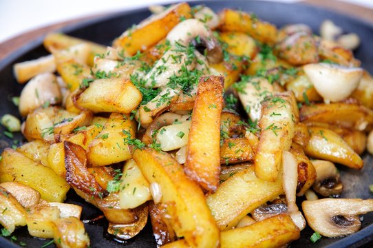 Fried potatoes with mushrooms in a skillet.