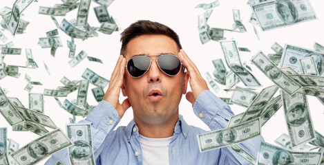 surprised man under dollar money rain
