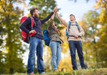 happy friends with backpacks making high five