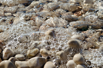 Sea wave and foam on pebble beach