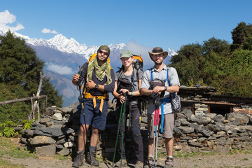 Three backpackers tourists posing, snow mountains peaks ridge.