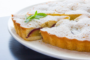 Plum cake dusted with icing sugar, a slice cut