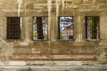 Old wall of a building with four windows and grilles