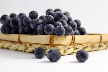 blue grapes in a basket on a white background 