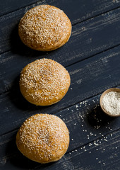 homemade buns for hamburgers on dark wooden surface