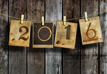 New year 2016 in old photo hanging on clothesline on wood background.