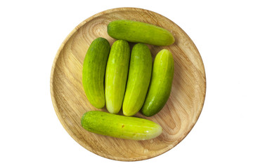 fresh cucumber in wooded plate on white background
