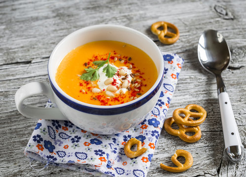 pumpkin soup with paprika and cream and crackers on a light wooden surface