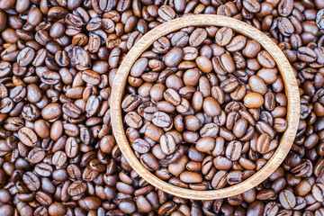 Coffee beans in wooden bowl on coffee beans background