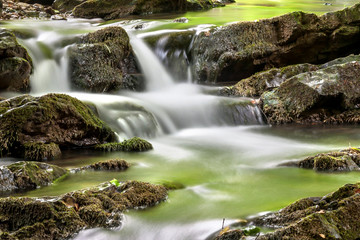 Silky water cascading over green moss-covered.