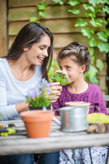 What do you smell? mother and daughter are repotting plants at the garden table.
