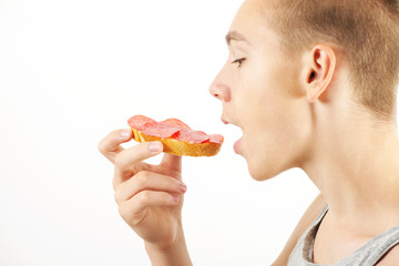 Young man eats small snack, opened mouth, side view