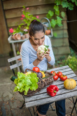 Woman with fresh vegetables in a basket at the garden table