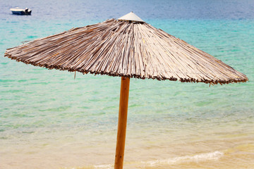 Straw Beach Umbrella and boat against blue sea,ocean. Summer, holiday, vacation background