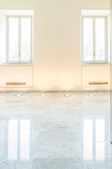 Bright clear gallery wall with two windows and marble floor