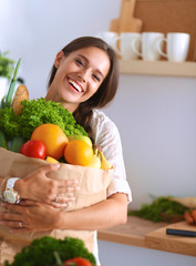 Young woman holding grocery shopping bag with vegetables 