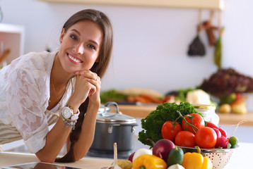 Young woman using a tablet computer to cook in her kitchen