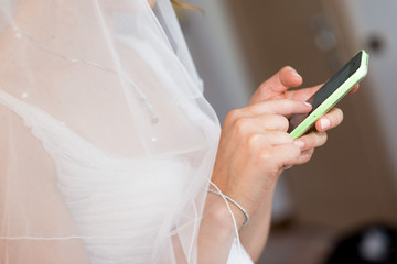 Sposa  con velo bianco che usa lo smartphone