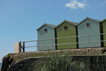 A bunch of green beach huts, blue sky, summer holidays