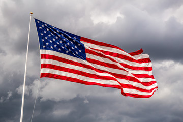 Brightly lit USA flag on a windy day against clouds