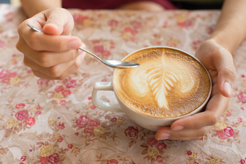 Close up image of woman shaking her favorite tasty hot art latte