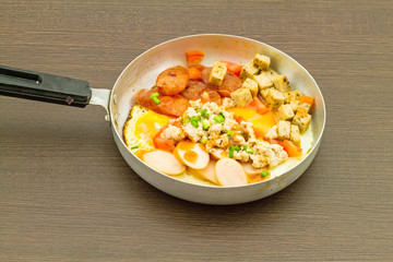 Indochina pan-fried egg with toppings in pan on black wooden