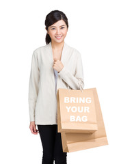 Young woman holding shopping bag and showing bring your bag
