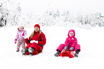 mother and her little daughters with bobs in snow