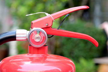 Close- up Fire extinguisher red tank with green background.