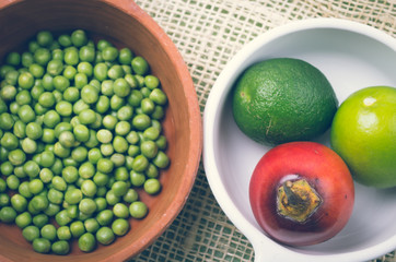 ceramic terracota bowl with raw green peas next to white plate
