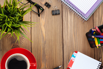 Office table with flower, blank notepad and coffee cup