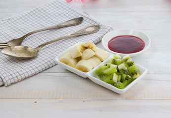 Raspberry jam with kiwi and banana over wooden vintage background