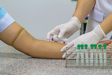 Blood test from venous vein  of patient by female doctor in white glove 
