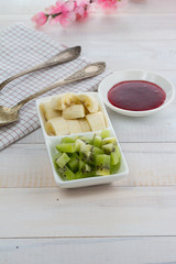 Raspberry jam with kiwi and banana over wooden vintage background