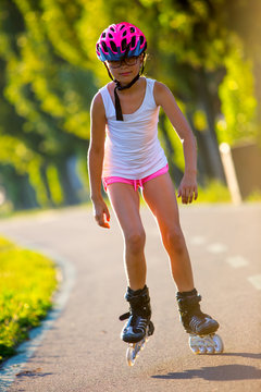 Rollerblading. Roller skating young girl in park rollerblading on inline skates. Caucasian young girl in sports activities.