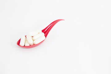 vitamin in red spoon on isolated background