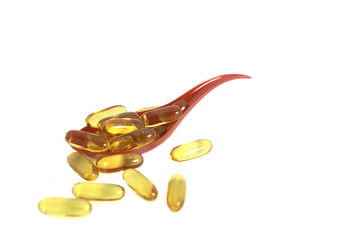 Cod liver oil omega 3 gel capsules isolated on red spoon backgro