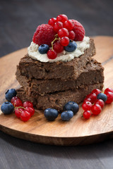 chocolate brownie cake with nuts and berries on wooden board