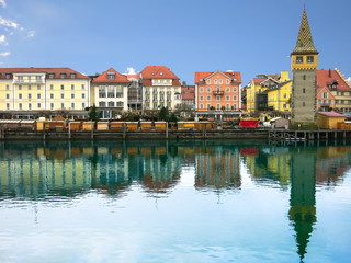 Fototapeta premium Harbour promenade in Lindau with reflection in the water in the sunny day. Tower Mangenturm. Bavaria, Germany, Europe.
