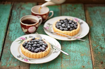 Tasty cakes with fresh wild blackberries and icing sugar with tw