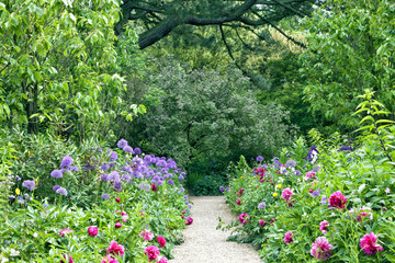 Stone garden path in the middle of summer cottage flowers, shrubs, trees - 90382645