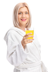 Young girl in a bathrobe holding an orange juice