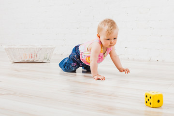 Little child crawling to cubes on floor