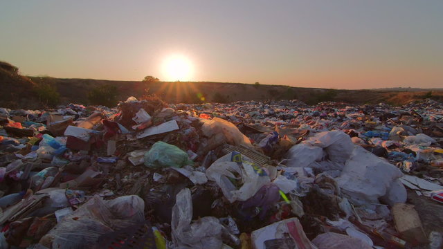 Sun setting over landfill site of domestic waste pan shot