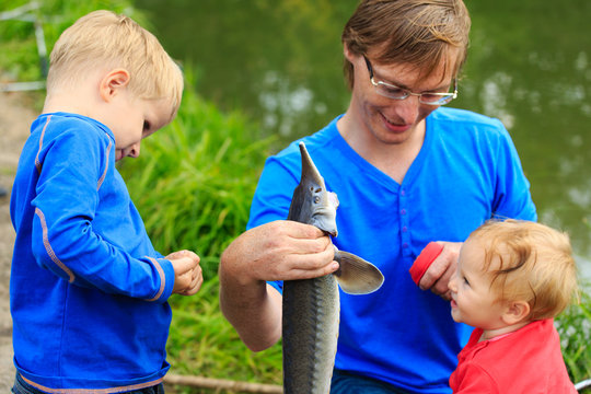 father and kids holding fish they caught on the lake