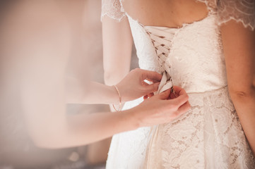 Bridesmaid helping the bride to dress
