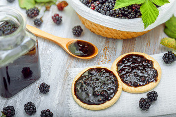 Fototapeta na wymiar Fresh blackberries with jam sandwich biscuits on table