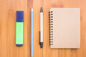 Pens, pencils and notebooks arranged on a wooden table with vintage style.
